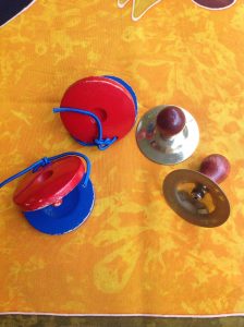 A pair of red and blue wooden castanets and a pair of finger cymbals with wooden knobs